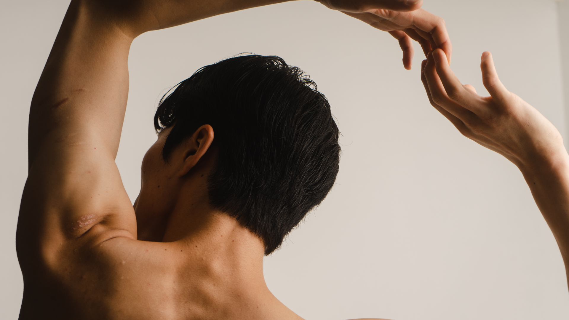 Man raising his arm behind his head while his shoulder is assessed Man raising his arm behind his head while his shoulder is assessed