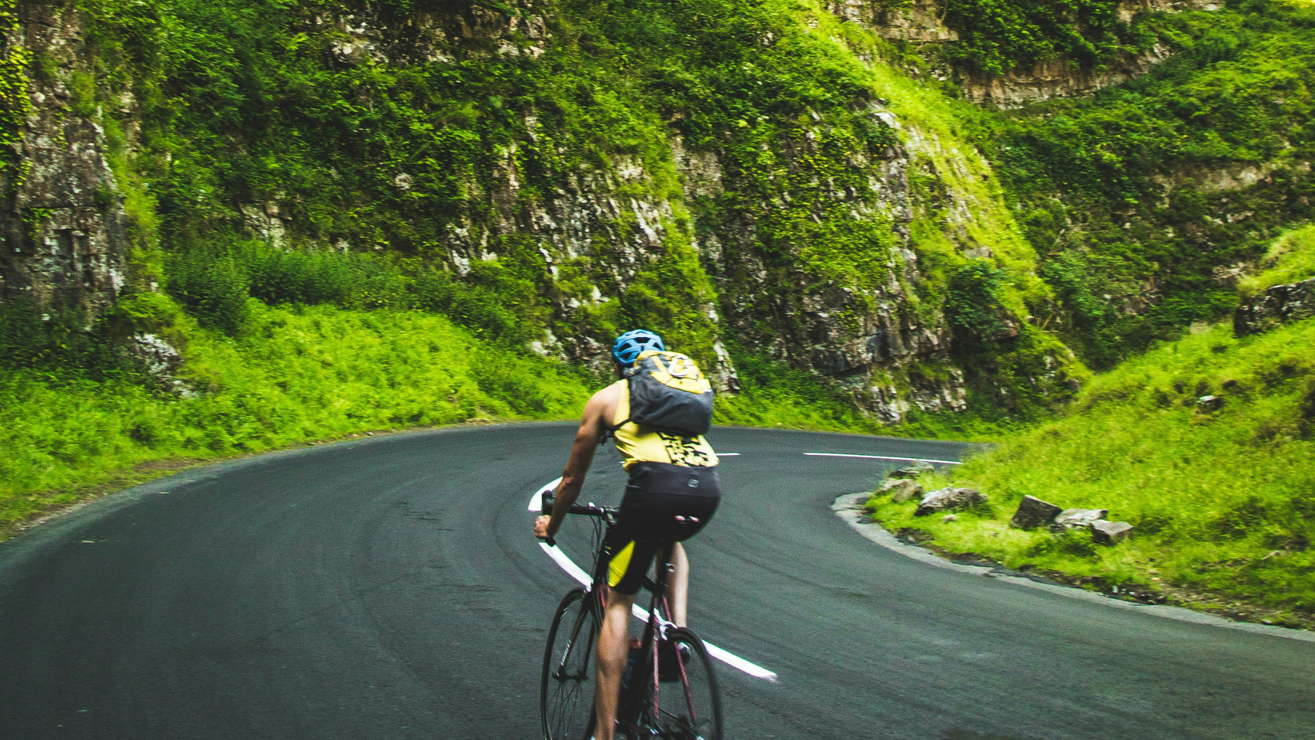 Cyclist riding on a winding mountain road Cyclist riding on a winding mountain road