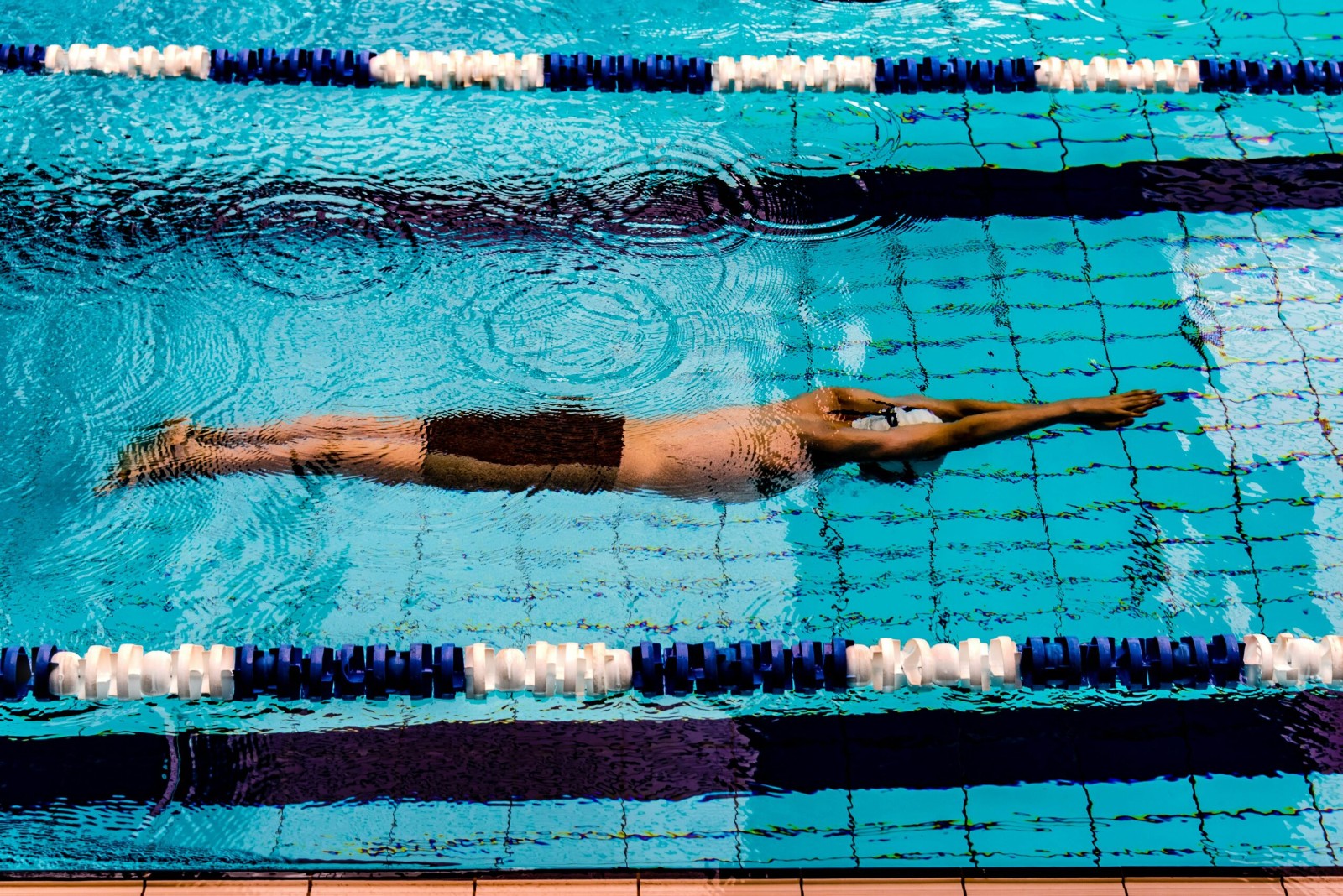 Swimmer gliding underwater in a lane of a swimming pool